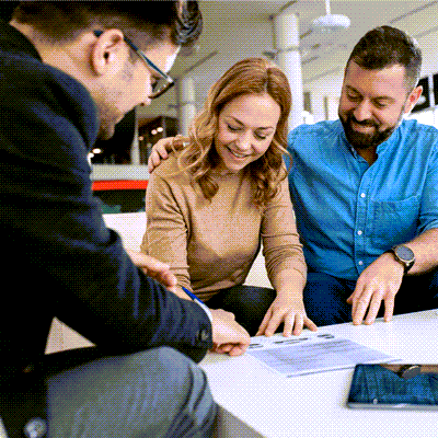 Couple talking with sales agent and signing contract for new car in modern car showroom